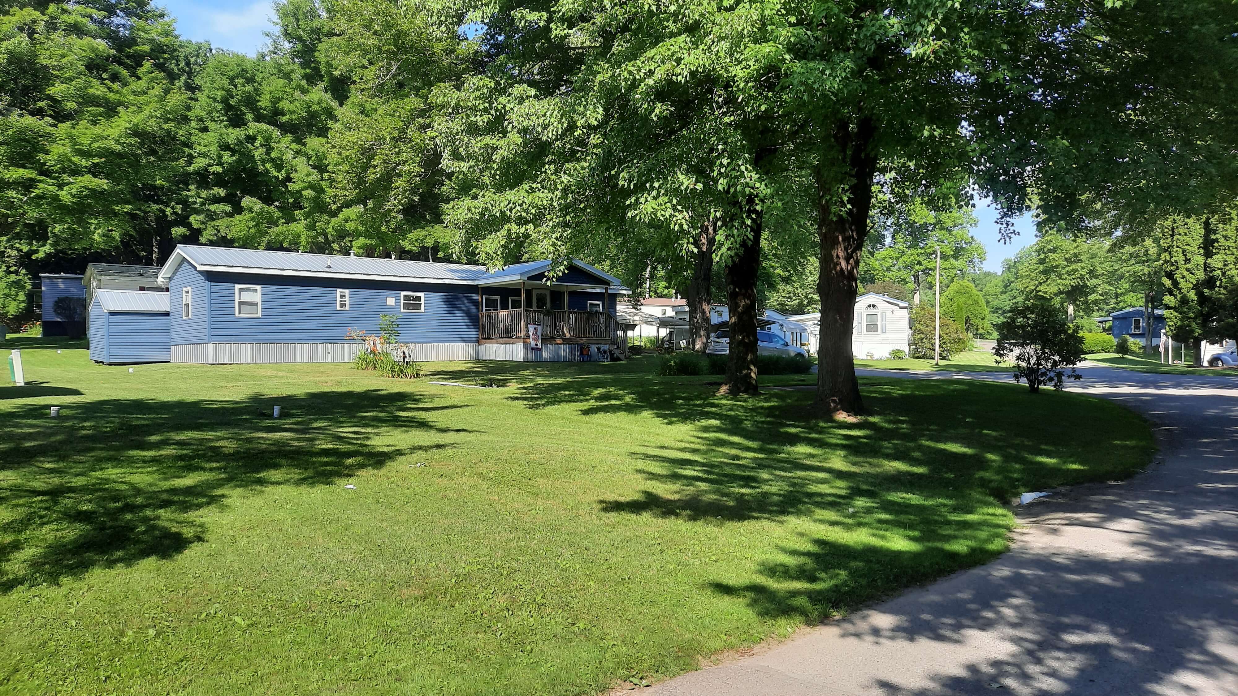 Blue mobile home with large yard and trees